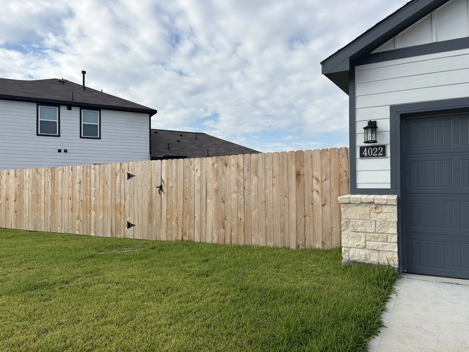 Finished wood fence and gate beside a gray garage